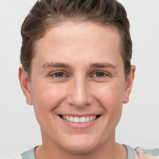 Joyful white young-adult male with short  brown hair and grey eyes