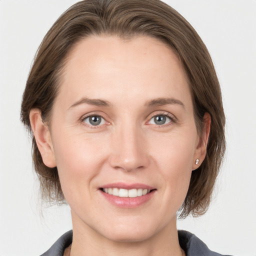 Joyful white young-adult female with medium  brown hair and grey eyes