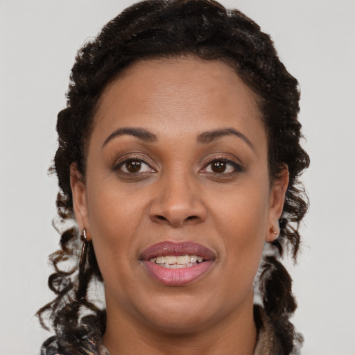 Joyful black young-adult female with long  brown hair and brown eyes