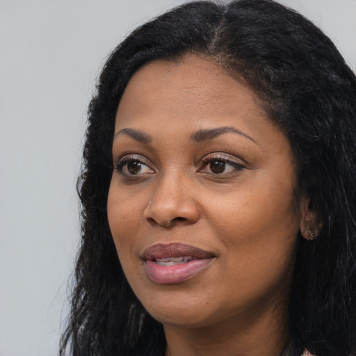 Joyful black adult female with long  black hair and brown eyes