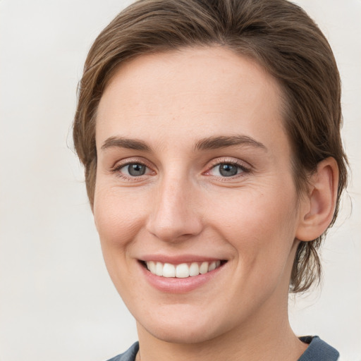 Joyful white young-adult female with short  brown hair and grey eyes