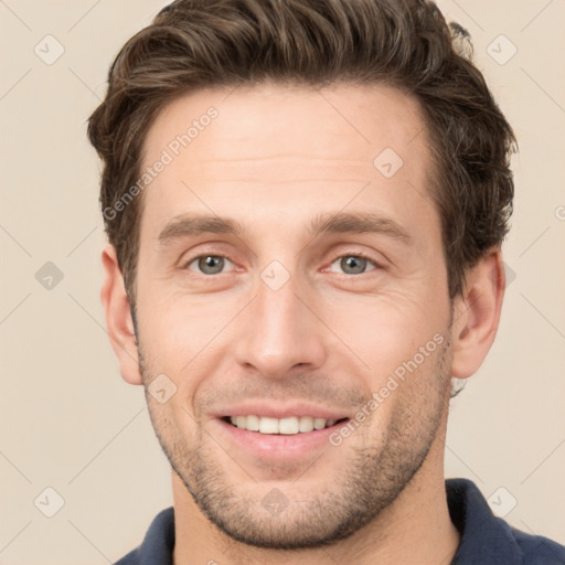 Joyful white young-adult male with short  brown hair and grey eyes