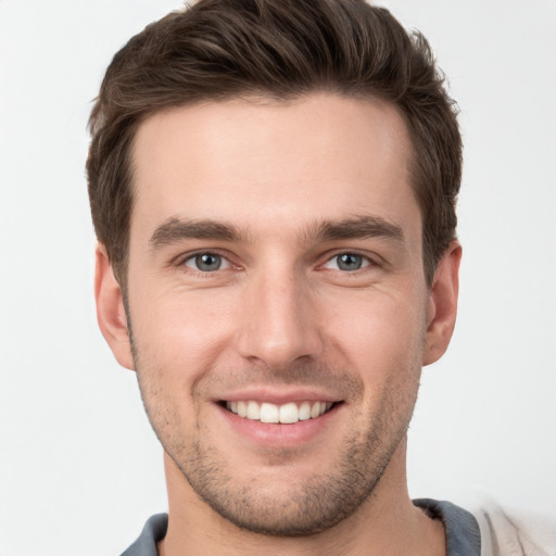 Joyful white young-adult male with short  brown hair and grey eyes