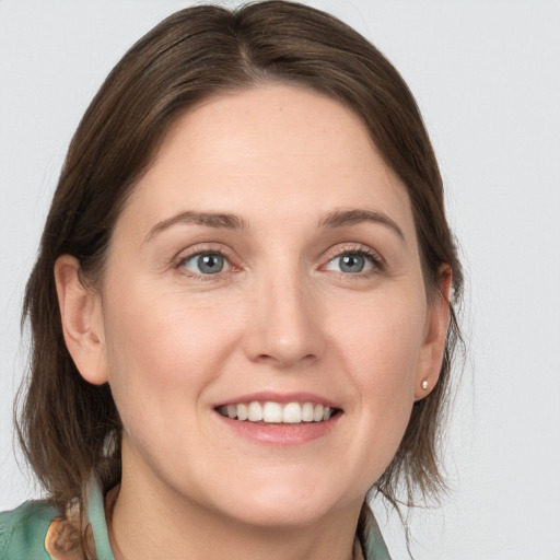 Joyful white young-adult female with medium  brown hair and grey eyes