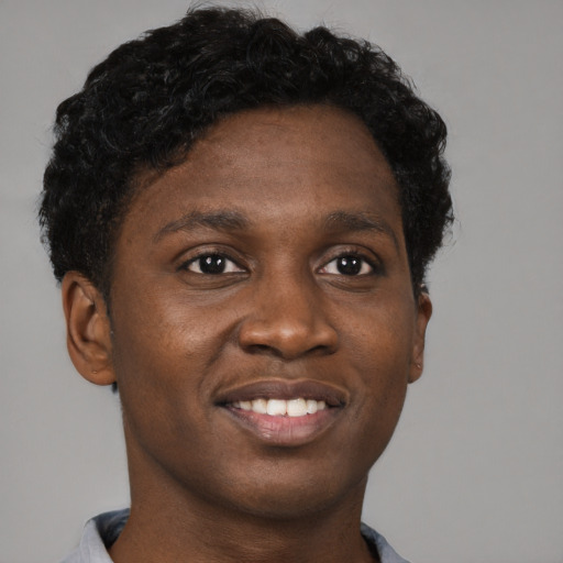 Joyful black young-adult male with short  brown hair and brown eyes