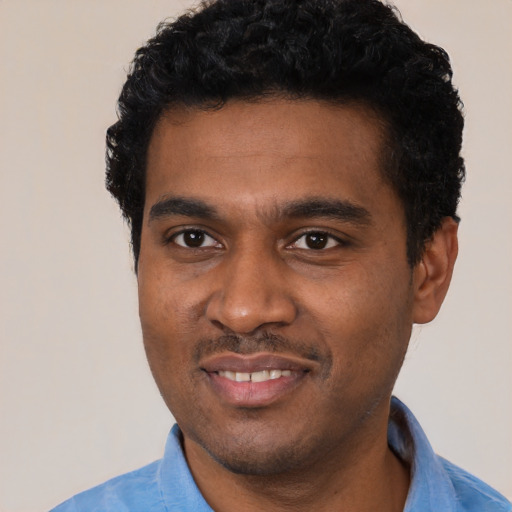Joyful black young-adult male with short  black hair and brown eyes