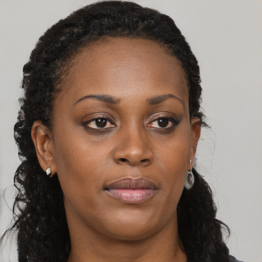 Joyful black young-adult female with long  brown hair and brown eyes