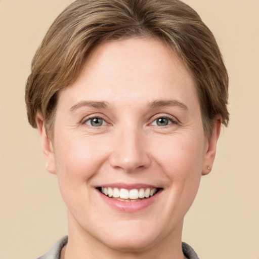 Joyful white young-adult female with short  brown hair and grey eyes