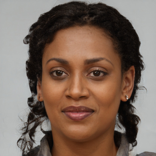Joyful black young-adult female with long  brown hair and brown eyes