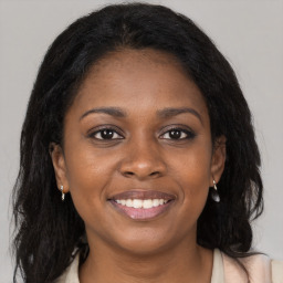 Joyful black young-adult female with long  brown hair and brown eyes