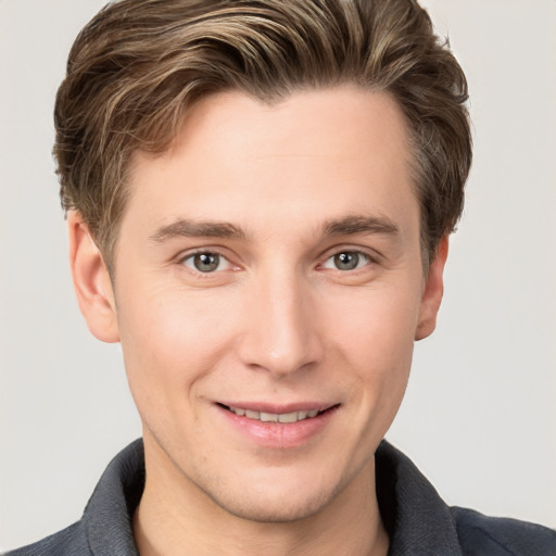 Joyful white young-adult male with short  brown hair and grey eyes