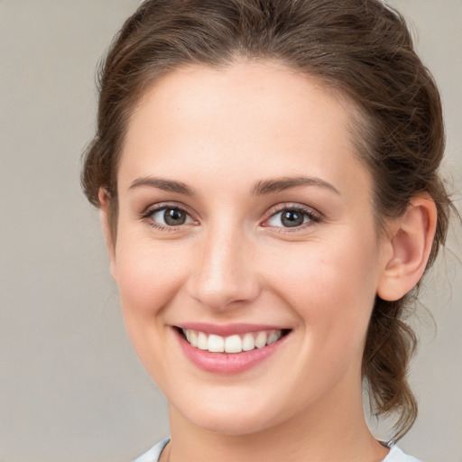 Joyful white young-adult female with medium  brown hair and grey eyes