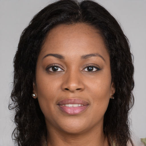 Joyful black young-adult female with long  brown hair and brown eyes