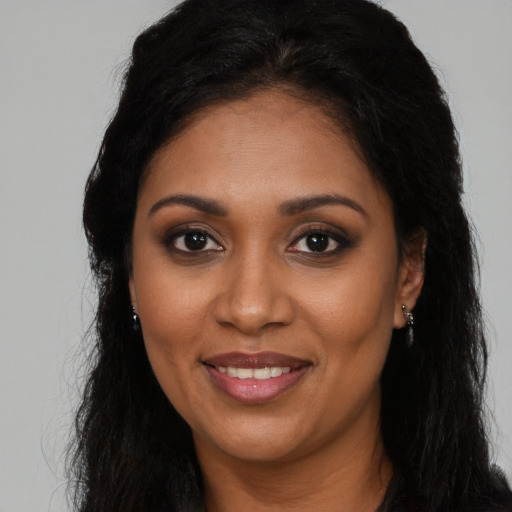 Joyful black young-adult female with long  brown hair and brown eyes