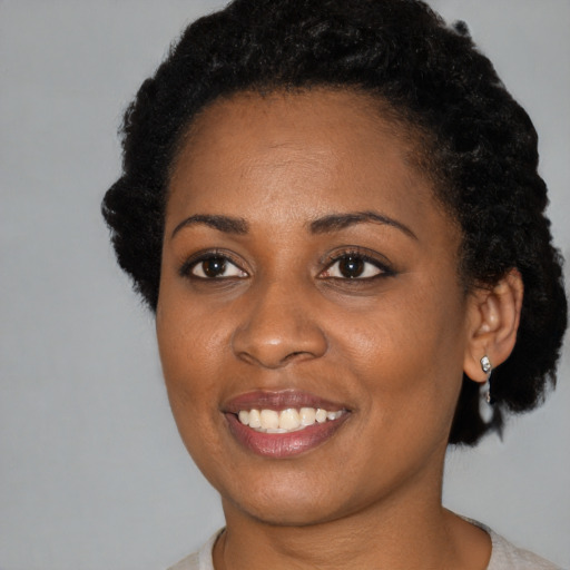 Joyful black young-adult female with short  black hair and brown eyes