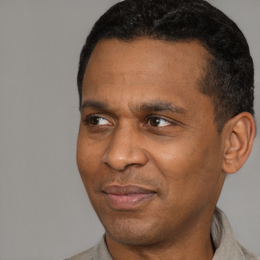 Joyful black adult male with short  black hair and brown eyes