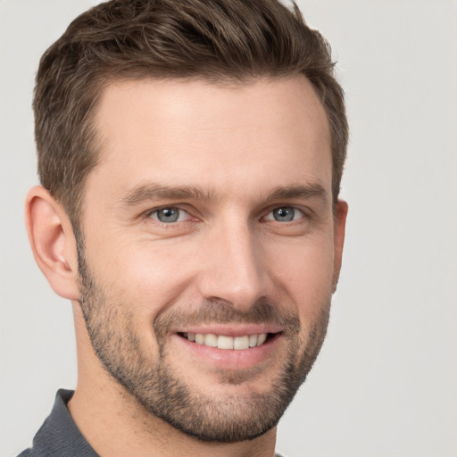 Joyful white young-adult male with short  brown hair and grey eyes