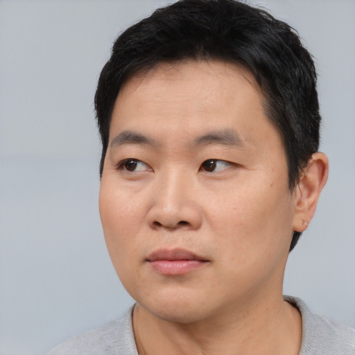 Joyful asian young-adult male with short  black hair and brown eyes