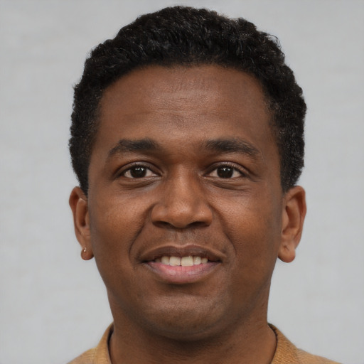 Joyful black young-adult male with short  brown hair and brown eyes