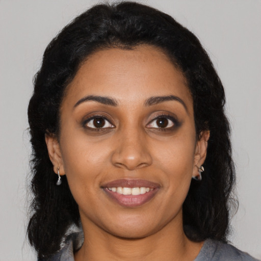 Joyful black young-adult female with long  black hair and brown eyes