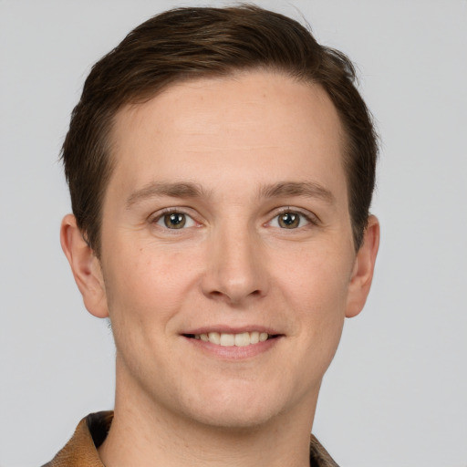 Joyful white young-adult male with short  brown hair and grey eyes