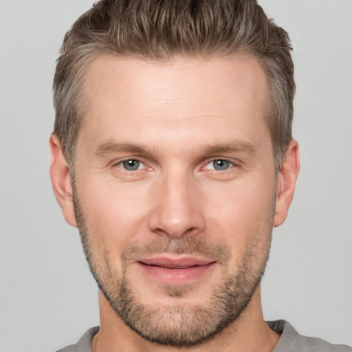 Joyful white young-adult male with short  brown hair and grey eyes