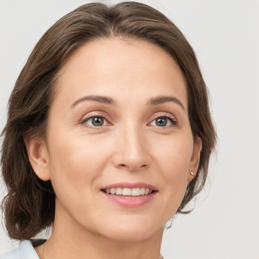 Joyful white young-adult female with medium  brown hair and grey eyes