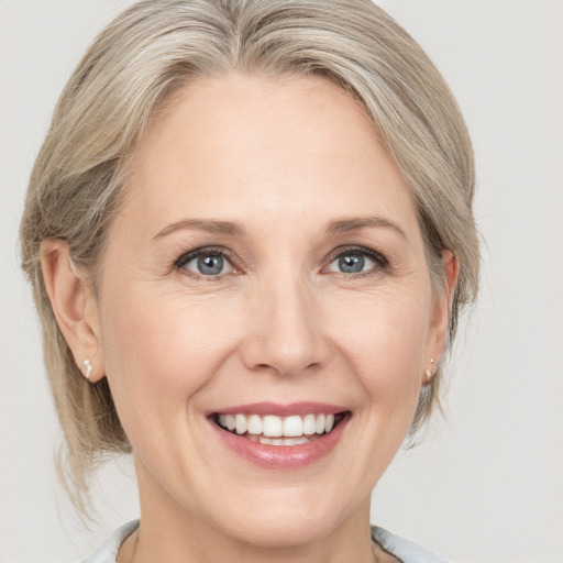 Joyful white adult female with medium  blond hair and grey eyes