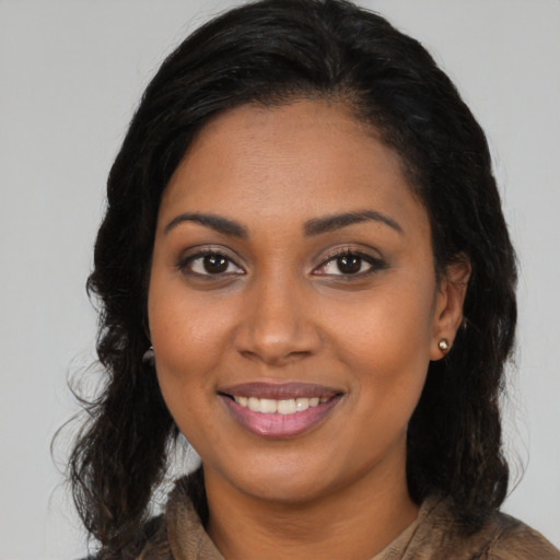 Joyful black young-adult female with long  brown hair and brown eyes