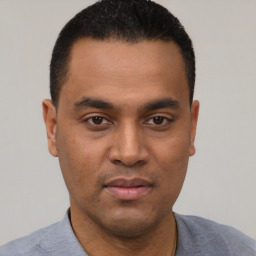 Joyful latino young-adult male with short  black hair and brown eyes