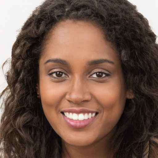 Joyful black young-adult female with long  brown hair and brown eyes