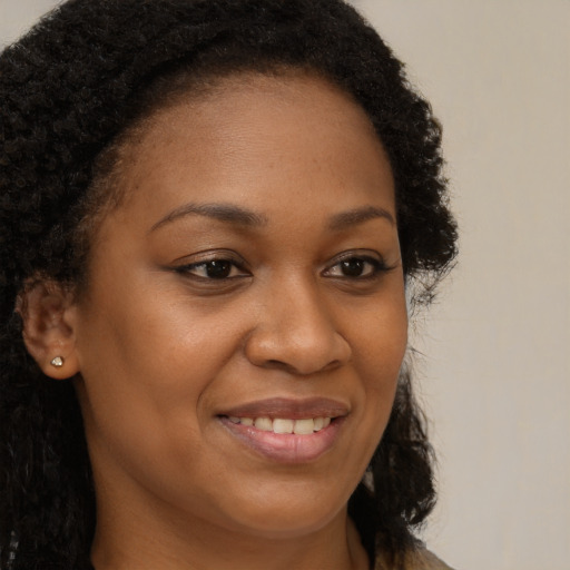 Joyful black young-adult female with long  brown hair and brown eyes