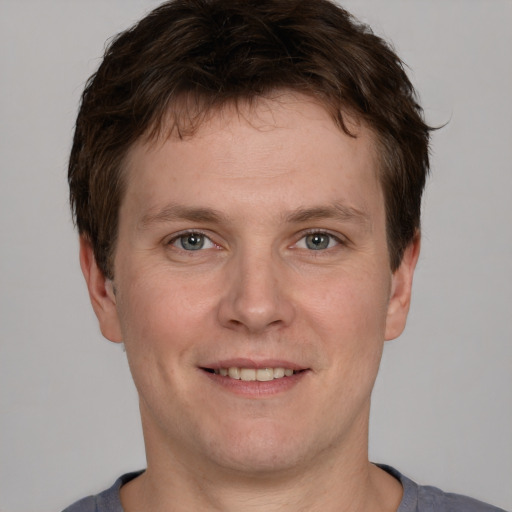 Joyful white young-adult male with short  brown hair and grey eyes