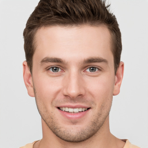 Joyful white young-adult male with short  brown hair and grey eyes