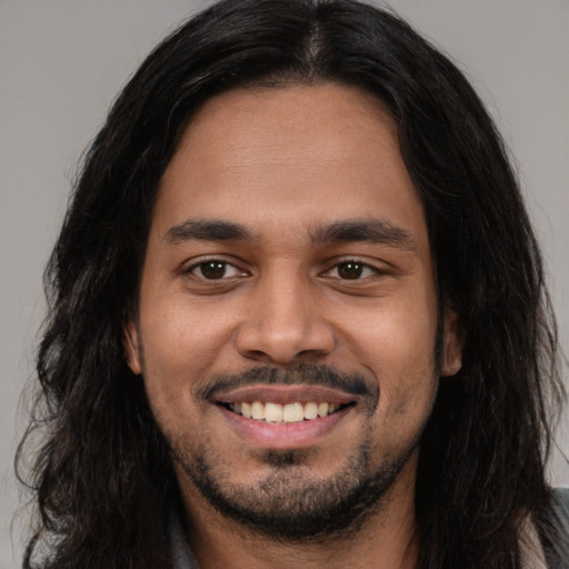 Joyful latino young-adult male with long  black hair and brown eyes