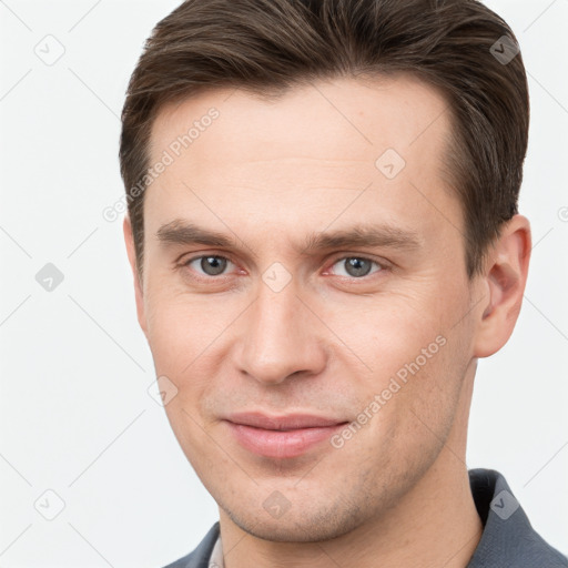 Joyful white young-adult male with short  brown hair and grey eyes