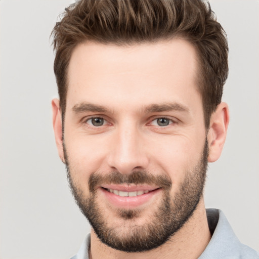 Joyful white young-adult male with short  brown hair and grey eyes