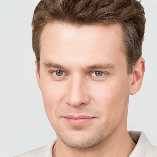 Joyful white young-adult male with short  brown hair and grey eyes