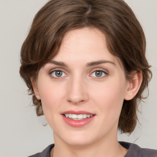 Joyful white young-adult female with medium  brown hair and grey eyes