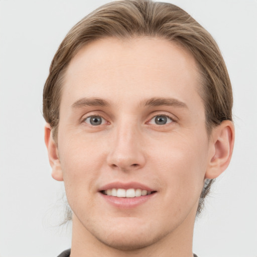 Joyful white young-adult male with medium  brown hair and grey eyes