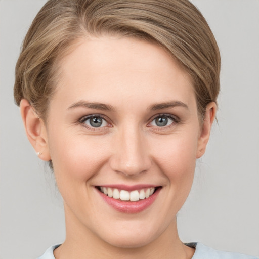 Joyful white young-adult female with medium  brown hair and grey eyes