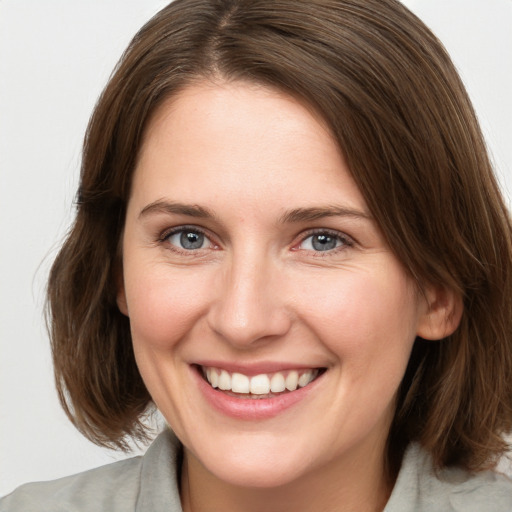 Joyful white young-adult female with medium  brown hair and grey eyes