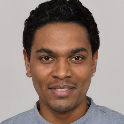 Joyful black young-adult male with short  black hair and brown eyes