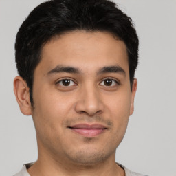 Joyful latino young-adult male with short  brown hair and brown eyes