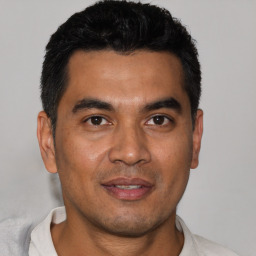 Joyful latino young-adult male with short  black hair and brown eyes