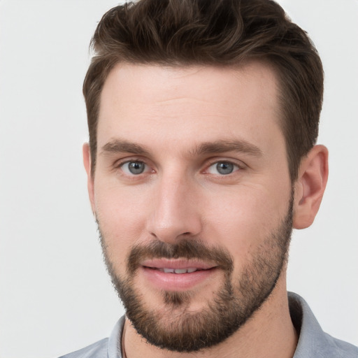 Joyful white young-adult male with short  brown hair and grey eyes