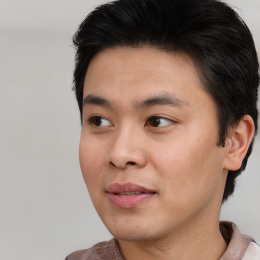 Joyful asian young-adult male with short  brown hair and brown eyes