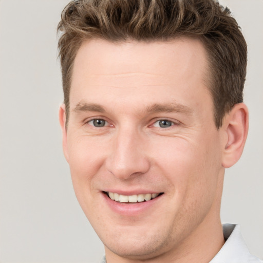 Joyful white young-adult male with short  brown hair and grey eyes