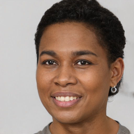 Joyful black young-adult female with short  brown hair and brown eyes