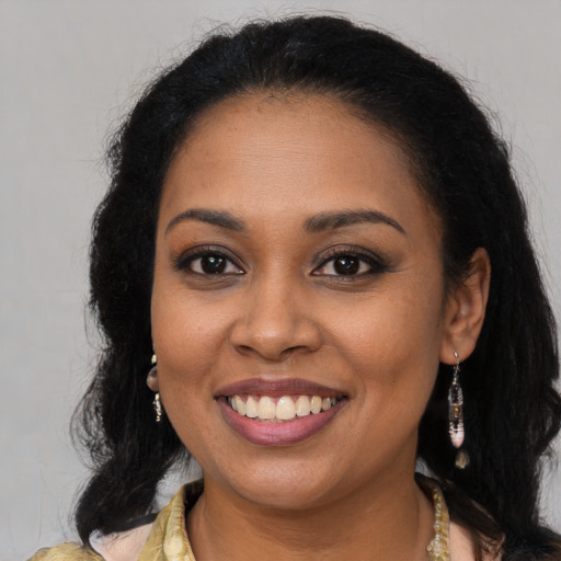 Joyful black young-adult female with long  brown hair and brown eyes